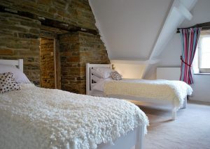 A twin room at that has a feature wall of exposed stone