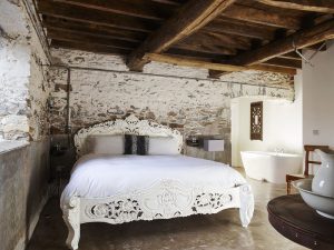 Polished concrete floors and rustic beams create a contemporary bedroom at Devon Farmhouse, to hire at The Big House Company