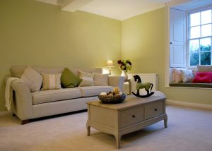 The sitting room with comfortable sofas, coffee table and large windows to the garden